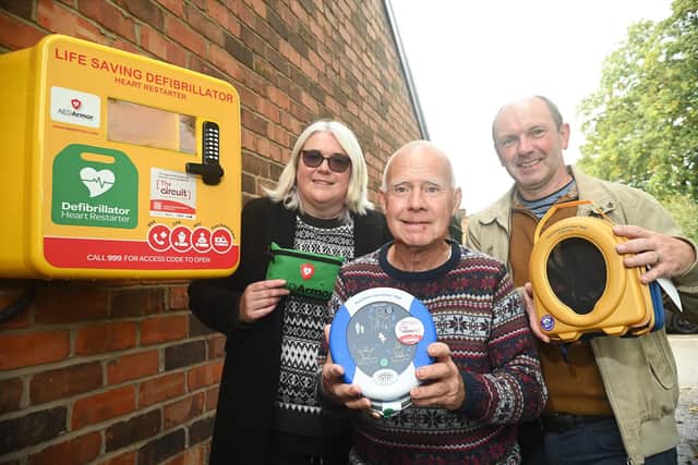 Andrew Moakes checks on the defibrillator outside St Anne's Parish Centre, Shevington, with councillors Vicky Galligan and Mike Crosby