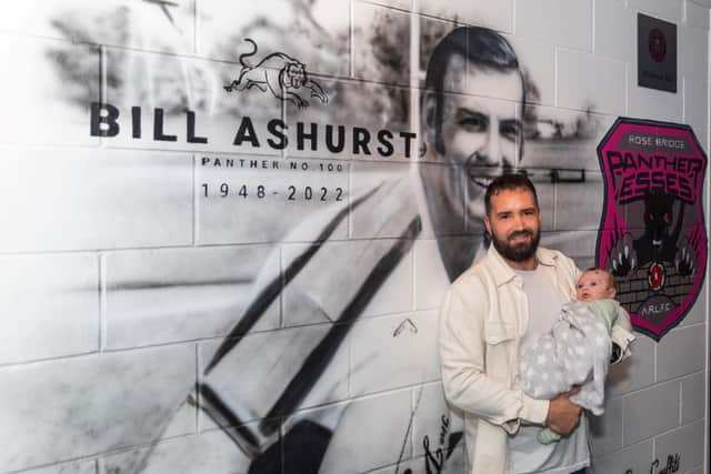 Nick Mapson, grandson of Bill Ashurst, with his new baby son Thor in front of the mural