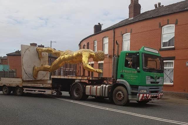 The naked golden statue seemingly does a 'Superman' on the back of a truck through the streets of Wigan as it is removed