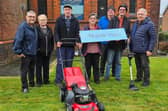 Councillors Chris Ready, left and Ron Conway, right, hand over the lawn mower at St John's Church