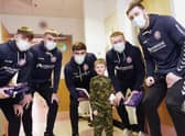 A young rugby fan meets Wigan Warriors players at the Rainbow children's ward at Wigan Infirmary.