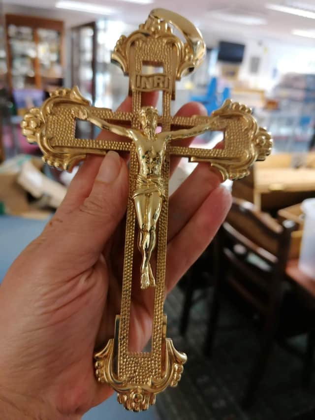 Hansons Auctioneers' trainee valuer Daniel Armstrong wears the chain. See SWNS story SWMRcross; The biggest gold crucifix and chain in the UK which weighs 1.5kg is set to fetch £30k at auction - with bling-loving boxers Tyson Fury and Anthony Joshua being offered first dibs.