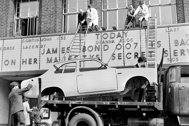 A Ford Escort car is hauled onto the roof section of the entrance to the ABC cinema in Station Road to publicise the latest James Bond film "On Her Majestys Secret Service" in 1970. Cinema manager, Derek Fuller, is on the roof, right.