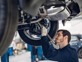 A gentleman fixing the oil sealant on his car's right carburettor or something