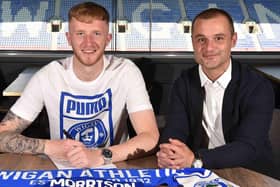 Liam Morrison puts pen to paper at the DW Stadium, flanked by Latics boss Shaun Maloney