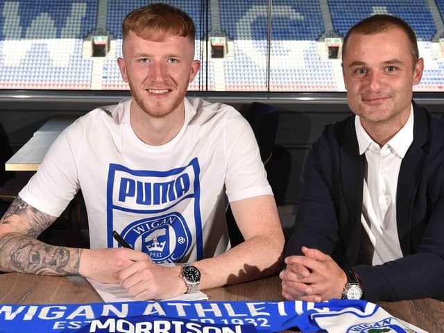 Liam Morrison puts pen to paper at the DW Stadium, flanked by Latics boss Shaun Maloney