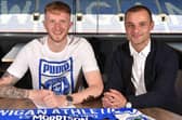 Liam Morrison puts pen to paper at the DW Stadium, flanked by Latics boss Shaun Maloney