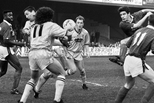 Wigan Athletic central defender Alan Johnson has a crack at goal against Preston North End watched by team-mates Don Page and Bryan Griffiths in a Division 3 match at Springfield Park on Tuesday 24th of April 1990. Latics lost the game 0-1.