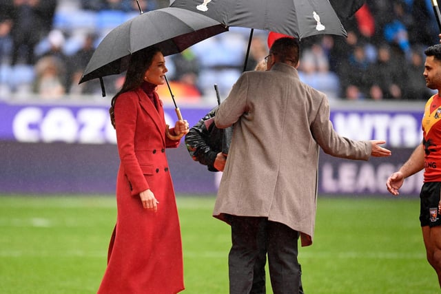 The Princess of Wales shelters from the rain under an umbrella as she comes out to meet the teams