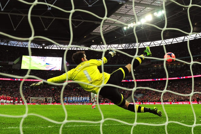 Santi Cazorla of Arsenal scores the winning penalty past Scott Carson of Wigan Athletic during the FA Cup Semi-Final match between Wigan Athletic and Arsenal at Wembley Stadium on April 12, 2014 in London, England.