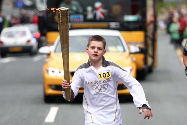 Torchbearer 103 carries the Olympic Flame on the Torch Relay leg between Wigan and Ince-in-Makerfield.