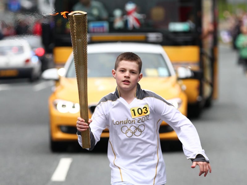 Torchbearer 103 carries the Olympic Flame on the Torch Relay leg between Wigan and Ince-in-Makerfield.