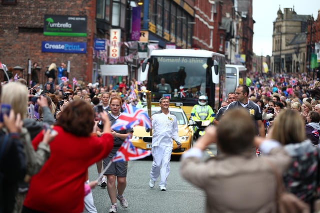 Thousands of people lined the streets to see the event as torchbearer 101 Norman Brown carries the Olympic Flame on the Torch Relay leg between Wigan and Ince-in-Makerfield.