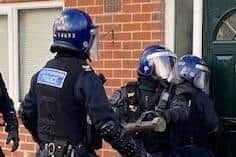 Police officers force their way into a house in Bryn
