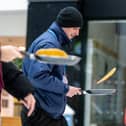 Ferocious concentration as competitiors speed-walk while continuously tossing their pancakes