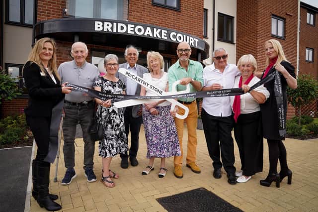 David Harper (with giant scissors) performs the ribbon-cutting ceremony at Brideoake Court