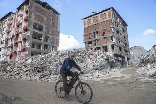 A man rides a bicycle past destroyed buildings in Antakya, southeastern Turkey, Tuesday, Feb. 21, 2023.