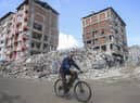 A man rides a bicycle past destroyed buildings in Antakya, southeastern Turkey, Tuesday, Feb. 21, 2023.
