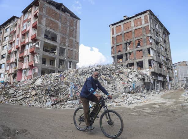 A man rides a bicycle past destroyed buildings in Antakya, southeastern Turkey, Tuesday, Feb. 21, 2023.