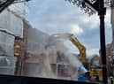 A digger tears at the familiar red brick surrounds of the Galleries