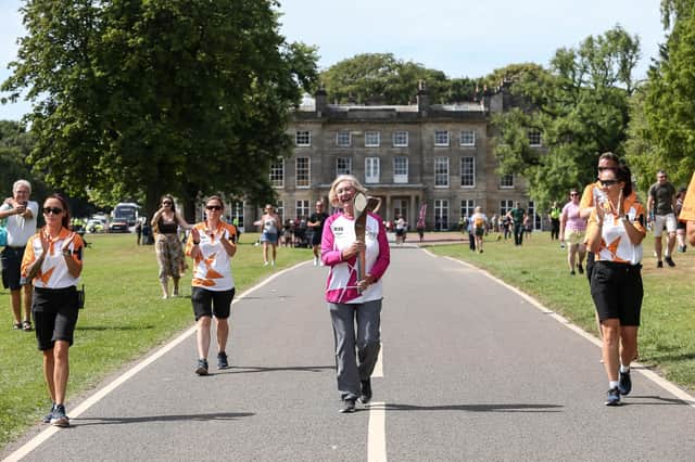 Batonbearer Joyce Fisher holds the Queen's baton at Haigh Woodland Park