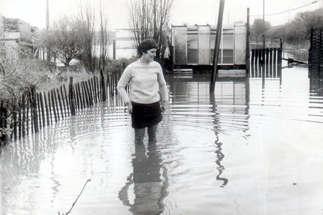 Mrs Sylvia Brazendale is not enjoying a seaside paddle but showing the depth of floodwater in the garden of her Wigan home in 1969.