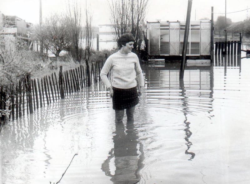 Mrs Sylvia Brazendale is not enjoying a seaside paddle but showing the depth of floodwater in the garden of her Wigan home in 1969.