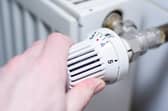 Close up of a person adjusting a heating thermostat.