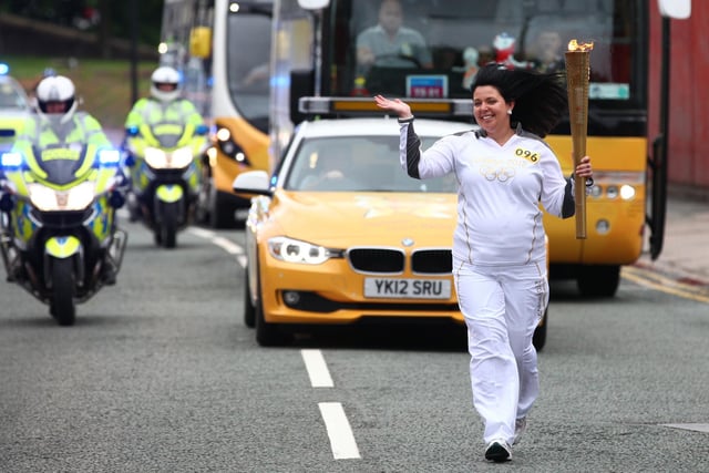 Torchbearer 096 Julie Clarke carries the Olympic Flame on the Torch Relay leg between Wigan and Ince-in-Makerfield.