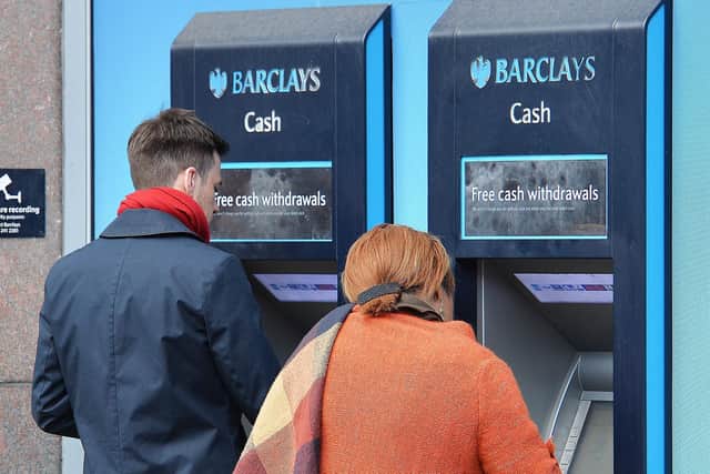Members of the public using cash machines to manage their money.