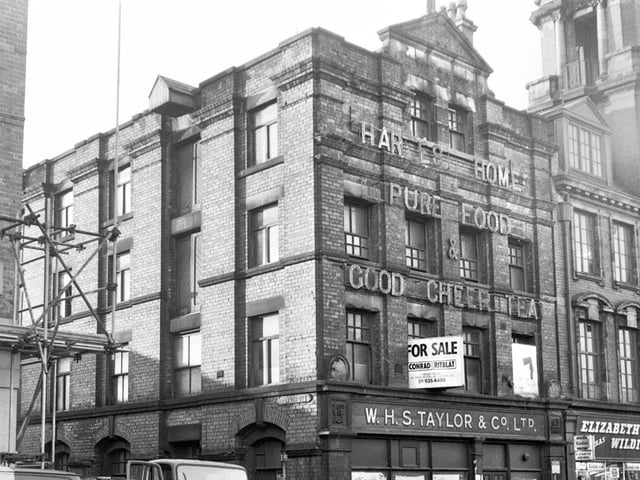 The derelict warehouse of W.H.S.Taylor on Market Street, Wigan, in 1971 with Elizabeth Wilding photographic shop next door and the Queen's Hall tower just visible.