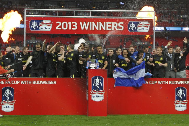Wigan Athletic players celerbate with the FA Cup after winning the English FA Cup final football match between Manchester City and Wigan Athletic at Wembley Stadium in London on May 11, 2013.
