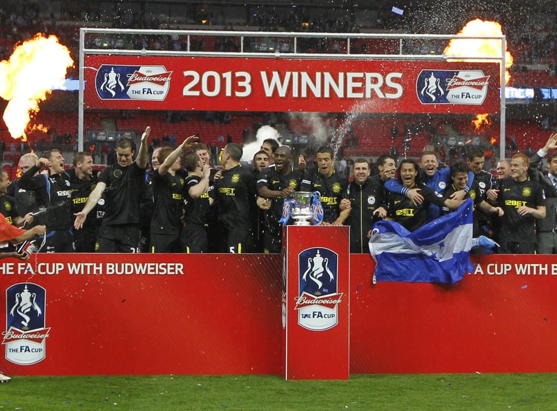Wigan Athletic players celerbate with the FA Cup after winning the English FA Cup final football match between Manchester City and Wigan Athletic at Wembley Stadium in London on May 11, 2013.