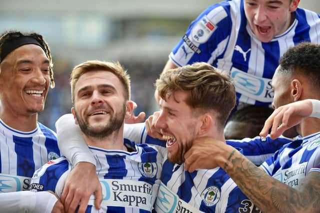 Callum Lang is mobbed after scoring Latics' second goal against Shrewsbury