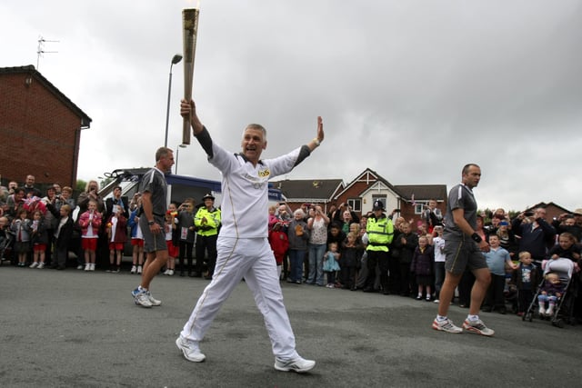 Torchbearer 105 Michael Anderson carries the Olympic Flame on the Torch Relay leg between Wigan and Ince-in-Makerfield.