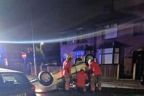 Firefighters work to make the overturned car safe