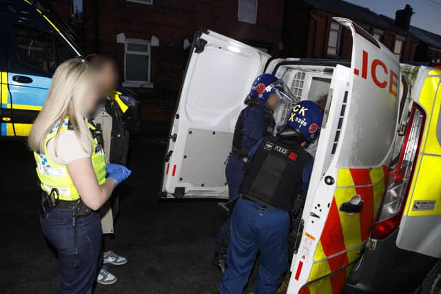 A suspect is put in the back of a police van after their arrest in Wigan