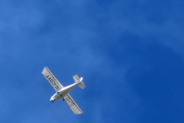 A plane flies overhead at Crosby Beach in clear blue skies