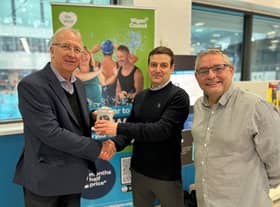 Leader of Wigan Council, Coun David Molyneux MBE (left) and Coun Chris Ready (right) present a Fitbit Sense 2 health tracker to Be Well member Christian Worthington - winner of Be Well's recent Thanks A Million prize draw celebrating more than a million visits to Be Well leisure centres in 2022.