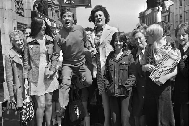 Legendary comic Norman Wisdom gets a lift up from Eileen Owen and Joan Vanes as he frolics with shoppers in Standishgate during an impromptu visit to Wigan town centre in May 1975.