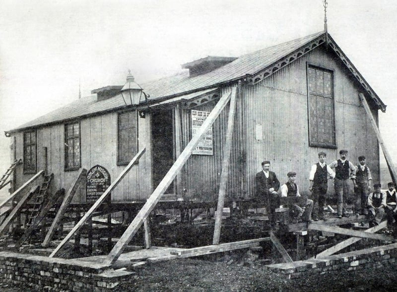 "Th'owd Tin Chapel" which preceded the present brick building of Gidlow Methodist Church on the corner of Barnsley Street and Buckley Street.
The picture shows the chapel being set in position around 1904 on what was then sandy wastes. The men in the picture are church officials and contractors. The iron church was demolished in 1949.