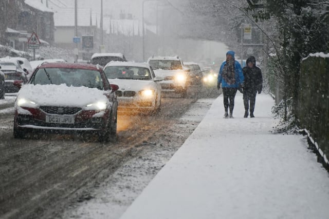 Motorists and pedestrians battle the elements as snow falls on Wigan Road,  Ashton-in-Makerfield.