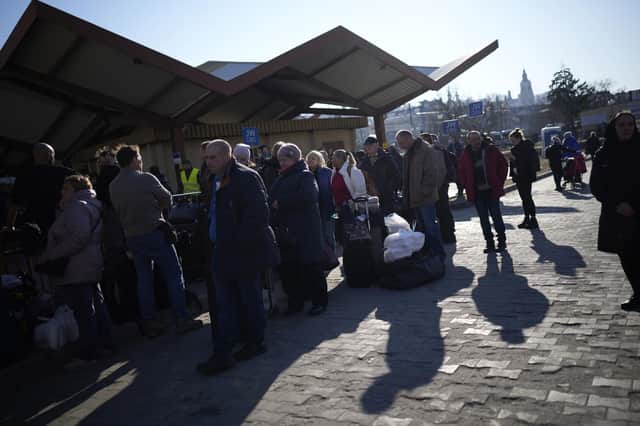People wait in a line to board a train leaving for Lviv in Ukraine at the train station in Przemysl, Poland, Monday, March 14, 2022. While tens of thousands of people have fled Ukraine every day since Russia's invasion, a small but growing number are heading in the other direction. At first they were foreign volunteers, Ukrainian expatriate men heading to fight and people delivering aid. But increasingly, women are also heading back.