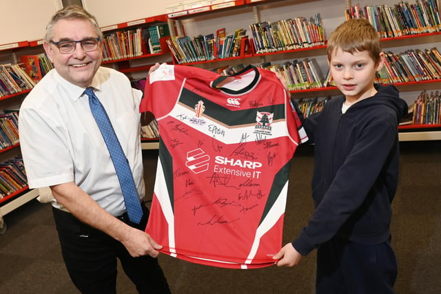 from left, Coun Chris Ready presents the signed rugby shirt to Year Five pupil Wilson, accepting it for the school.