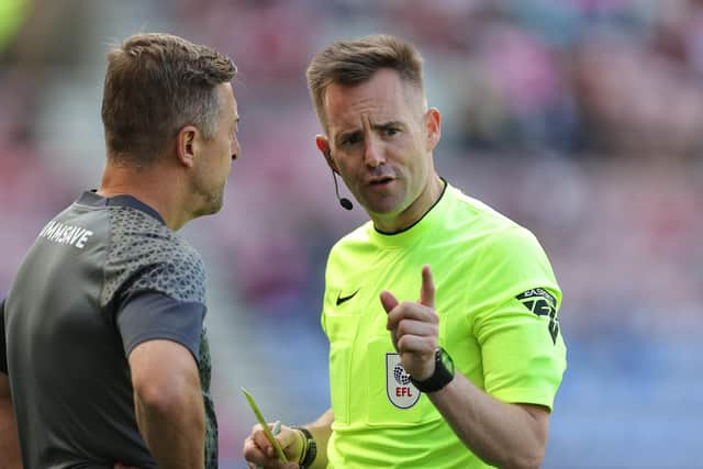 Northampton boss Jon Brady is yellow carded by referee Ross Joyce during Saturday's defeat against Latics at the DW