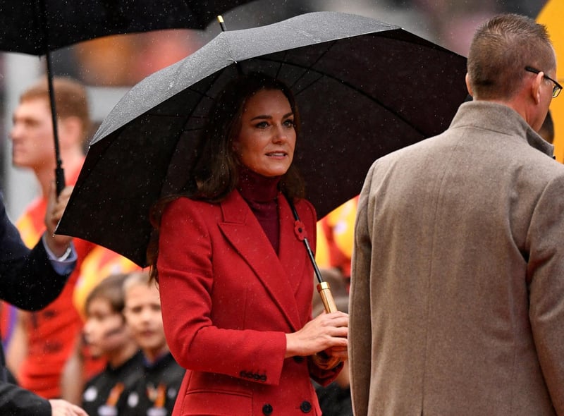 The Princess of Wales shelters from the rain under an umbrella as she comes out to meet the teams