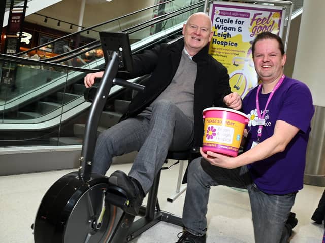 From left:  Mike Matthew, general manager at The Grand Arcade Shopping Centre, Wigan, on a static fitness bike, pictured with Chris Swinton, events and fundraising at Wigan and Leigh Hospice, as staff from the Grand Aracade and shoppers take turns to pedal a total of 2024km, part of the Feel Good February challenge, raising funds for the charity
