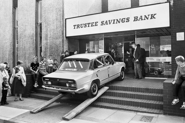 A Triumph Dolomite car from the Baldwin Timberlake garage is driven up the steps into the Trustee Savings Bank in King Street, Wigan, for a publicity stunt on Tuesday 22nd of July 1980.