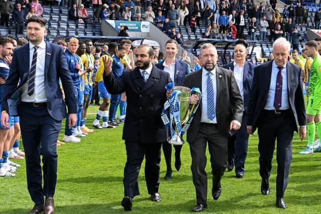 Talal Al Hammad and Mal Brannigan bring out the League One title, watched by EFL chief Rick Parry