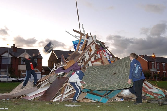 Youngsters play on a bonfire on Whitledge Green, Bryn, which has been built despite Council warning signs about the possible severe penalties and the presence of a nearby surveillance camera.